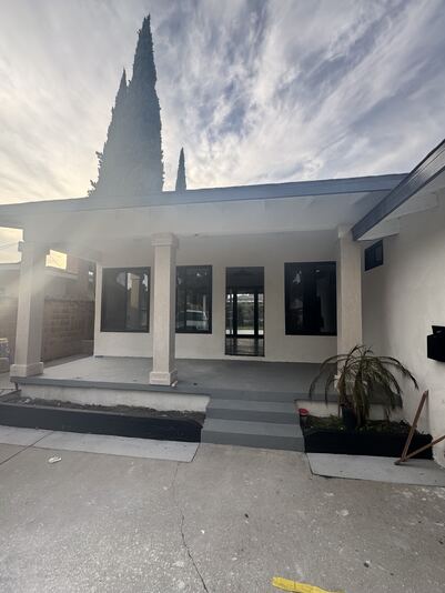 Covered front porch with concrete steps and black-framed windows