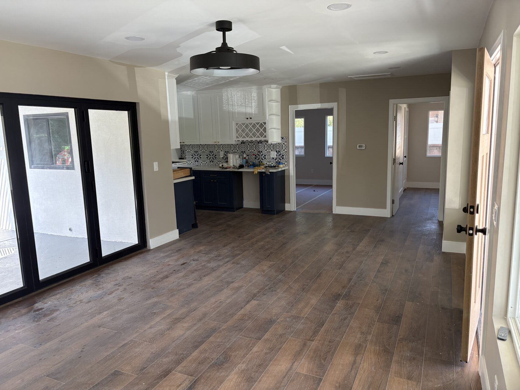 Open-concept living room and kitchen with dark wood floors and black-framed accordion doors at 2715 Petaluma
