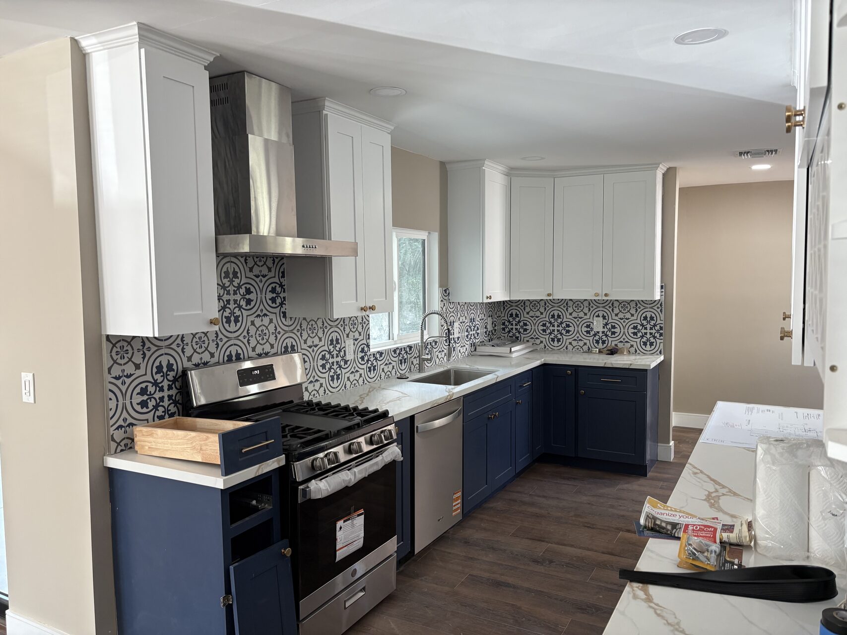 Close view of remodeled kitchen with navy cabinets, marble-look counters, and patterned tile