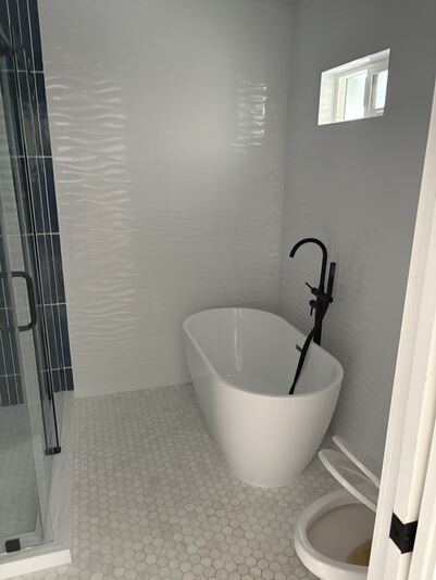 Modern bathroom with freestanding soaking tub, matte black filler, and hexagon floor tile